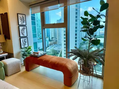 a brown leather bench in a room with a large window at Palms Paradise with the best view of BGC plus Netflix in Manila