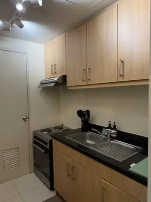 a kitchen with a sink and a stove and cabinets at Palms Paradise with the best view of BGC plus Netflix in Manila