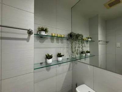 a bathroom with a toilet and a glass shelf with plants at Palms Paradise with the best view of BGC plus Netflix in Manila