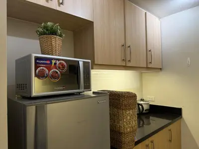 a microwave sitting on top of a refrigerator in a kitchen at Palms Paradise with the best view of BGC plus Netflix in Manila
