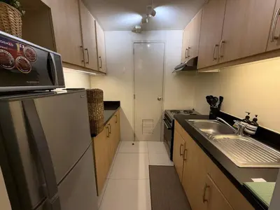 a small kitchen with a sink and a refrigerator at Palms Paradise with the best view of BGC plus Netflix in Manila