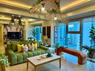a living room with a green couch and a chandelier at Palms Paradise with the best view of BGC plus Netflix in Manila