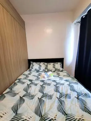 a bedroom with a bed with a black and white comforter at Wooden style amenities view in Manila