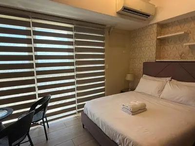 a bedroom with a bed and a table and a window at Deluxe Suite in Venice Mall in Manila