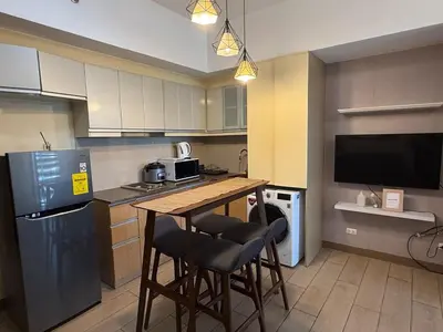 a kitchen with a table and two bar stools at Deluxe Suite in Venice Mall in Manila