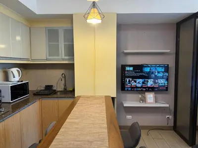 a kitchen with a table and a tv on the wall at Deluxe Suite in Venice Mall in Manila