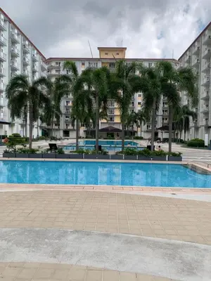 a swimming pool with palm trees in front of buildings at PEACETIME CONDO FIELD RESIDENCES BLDG 6 u1006B in Manila
