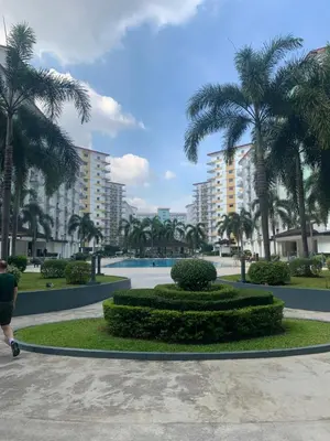 a person walking by a park with palm trees and buildings at PEACETIME CONDO FIELD RESIDENCES BLDG 6 u1006B in Manila