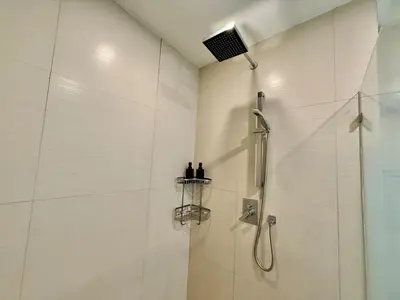 a bathroom with a shower with two bottles on a shelf at Spacious Tropics with Golf View in BGC in Manila