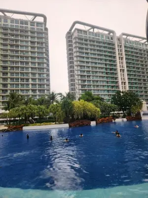 people swimming in a pool in front of two tall buildings at Azure Staycation Philippines by AMRS Near Manila International Airport in Manila