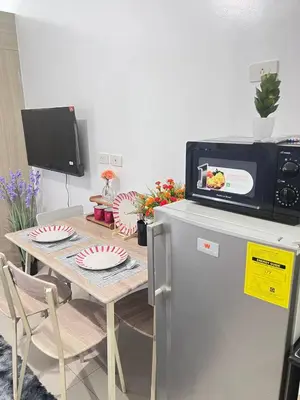 a dining room with a table and a microwave at Unistay SHORE Residence w Balcony Amazing Manila Bay view near MOA in Manila