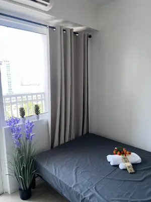a bedroom with a bed and a window with flowers at Unistay SHORE Residence w Balcon Amazing Manila Bay View in Manila