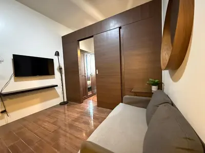 a living room with a couch and a flat screen tv at 1 BR Condo w Balcony in Air Residence Makati in Manila