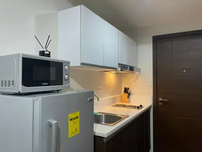 a kitchen with a microwave on top of a refrigerator at 1 BR Condo w Balcony in Air Residence Makati in Manila