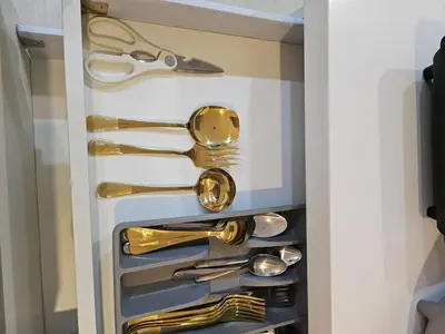 a drawer filled with gold utensils in a cabinet at Cozy Apartment Azure Urban Resort Residences in Manila