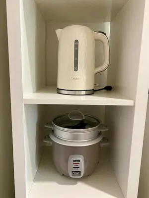 a coffee maker and a slow cooker in a cabinet at Condo unit near SM City Sta Rosa Unit 2 in Ibaba