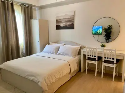 a bedroom with a bed and a desk and a mirror at Condo unit near SM City Sta Rosa Unit 2 in Ibaba