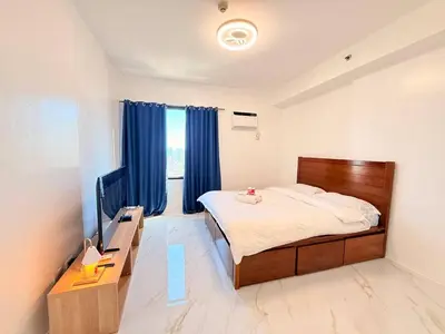 a bedroom with a bed and a tv and blue curtains at Malate Bayview Mansion Korean Town 1Bedroom in Manila