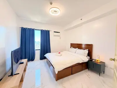 a bedroom with a large bed with blue curtains at Malate Bayview Mansion Korean Town 1Bedroom in Manila