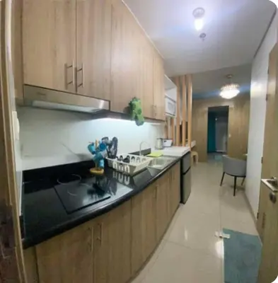 a kitchen with wooden cabinets and a black counter top at Modern Comfort at Shore 2 MOA in Manila