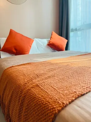 a bed with orange and white sheets and pillows at BGC Simple Elegant 300Mbps Wifi,Pool,Netflix in Manila