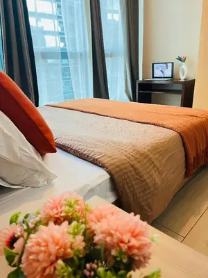 two beds in a hotel room with flowers on a table at BGC Simple Elegant 300Mbps Wifi,Pool,Netflix in Manila