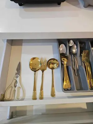 a drawer filled with gold spoons and forks and knives at Cozy Apartment Azure Urban Resort Residences in Manila