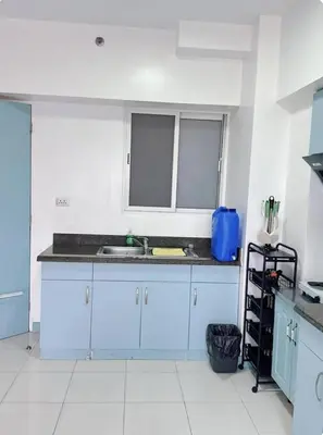 a kitchen with white cabinets and a sink at Torre de manila taft 23 in Manila