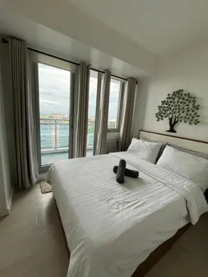 a teddy bear sitting on a bed in a bedroom at Azure Condo Maui by arlene in Manila