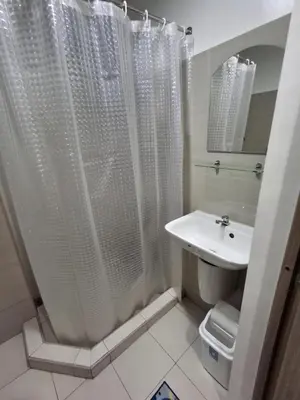 a bathroom with a white shower curtain and a sink at Staycation Modern & Convenient in Tubigan