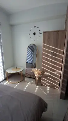 a bedroom with a clock on the wall and a table at Staycation Modern & Convenient in Tubigan