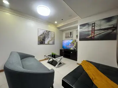 a living room with a couch and a tv at 2BR Grand Riviera Suites by MrSayla in Manila