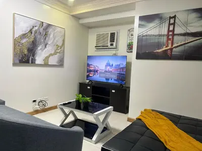 a living room with a couch and a tv at 2BR Grand Riviera Suites by MrSayla in Manila