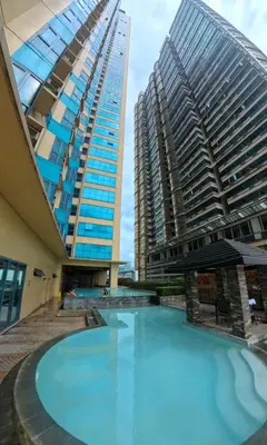 a large swimming pool in front of a tall building at 2BR Grand Riviera Suites by MrSayla in Manila