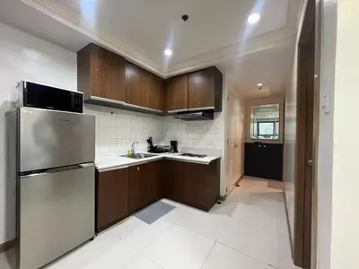 a kitchen with wooden cabinets and a stainless steel refrigerator at 2BR Grand Riviera Suites by MrSayla in Manila