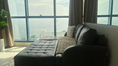a leather couch in a room with a large window at 2BR Grand Riviera Suites by MrSayla in Manila