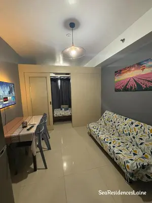 a room with a bed and a table and a desk at Sea Residences by Laine in Manila