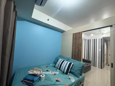 a living room with a couch and a blue wall at Sea Residences by Laine in Manila