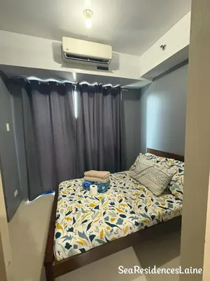a bedroom with a bed and a air conditioner at Sea Residences by Laine in Manila