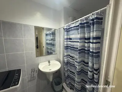 a bathroom with a sink and a shower curtain at Sea Residences by Laine in Manila