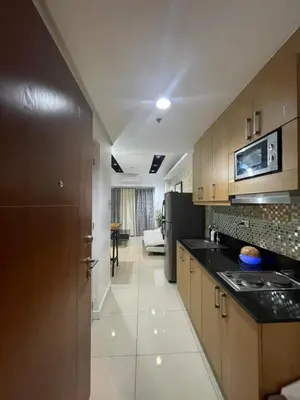 a kitchen with wooden cabinets and a black counter top at 2bedroom with 2balcony with pool view 1633-34 in Manila
