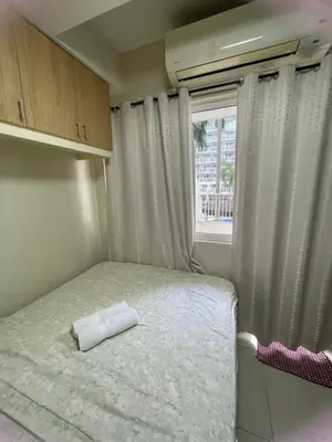 a small bedroom with a bed and a window at 1bedroom pool view with big balcony in Manila