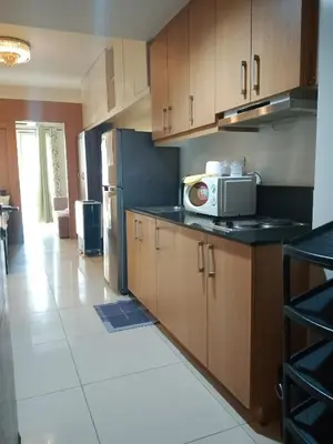 a kitchen with wooden cabinets and a microwave at 1bedroom pool view with big balcony in Manila