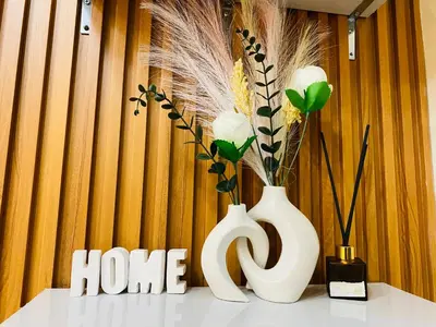 two white vases sitting on a table with flowers at Condotel at S Residences near SM MOA, SMX, Arena, NAIA Airport in Manila