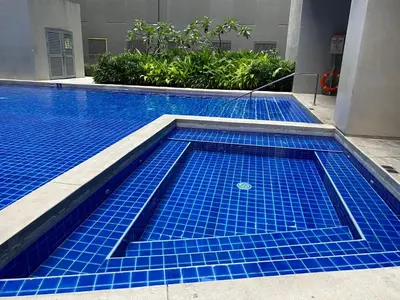 a swimming pool with blue tiles in a building at Condotel at S Residences near SM MOA, SMX, Arena, NAIA Airport in Manila
