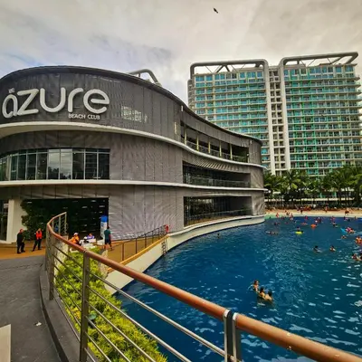 a swimming pool in front of a building with people in it at Azure Urban Resort Residences by Moldez Staycation in Manila