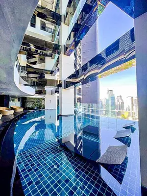 a swimming pool in a building with a view of a city at Cozy Apartment City & Mountain View with balcony FREE use of pools sauna and sunbathing in Manila