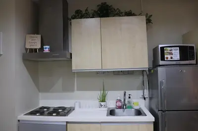 a kitchen with a sink and a microwave and a refrigerator at Cozy Apartment City & Mountain View with balcony FREE use of pools sauna and sunbathing in Manila
