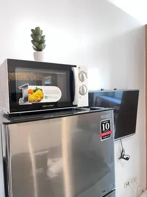 a microwave sitting on top of a refrigerator at Unistay SHELL Residences Amazing Pool view near MOA in Manila