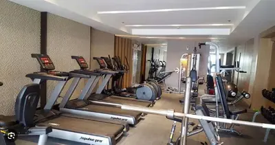 a gym with a bunch of cardio equipment in a room at Unistay SHELL Residences Amazing Pool view near MOA in Manila